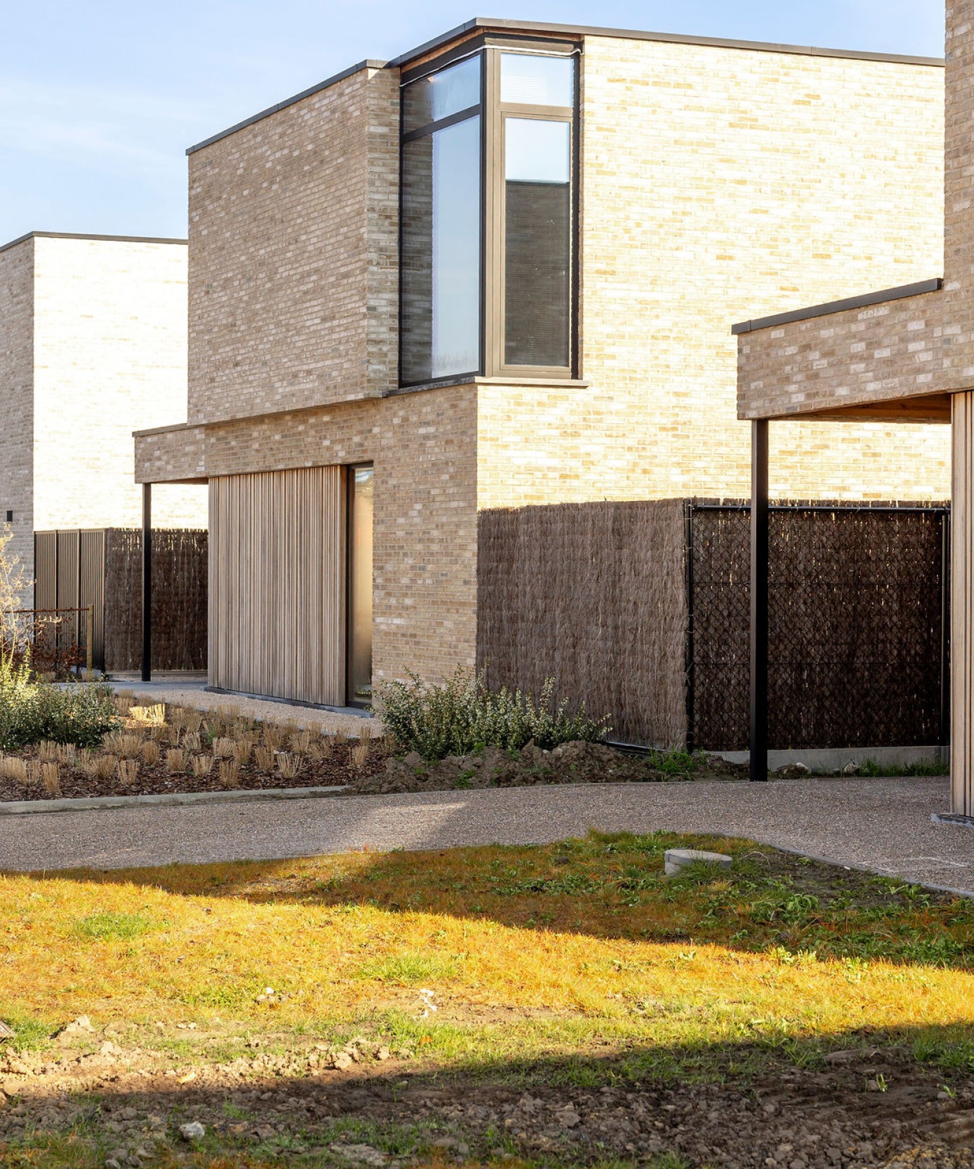 Nieuwbouwwoningen met carports met doorlopende gevelbekleding in steenstrips