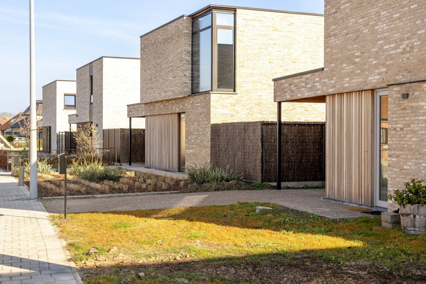 Nieuwbouwwoningen met carports met doorlopende gevelbekleding in steenstrips